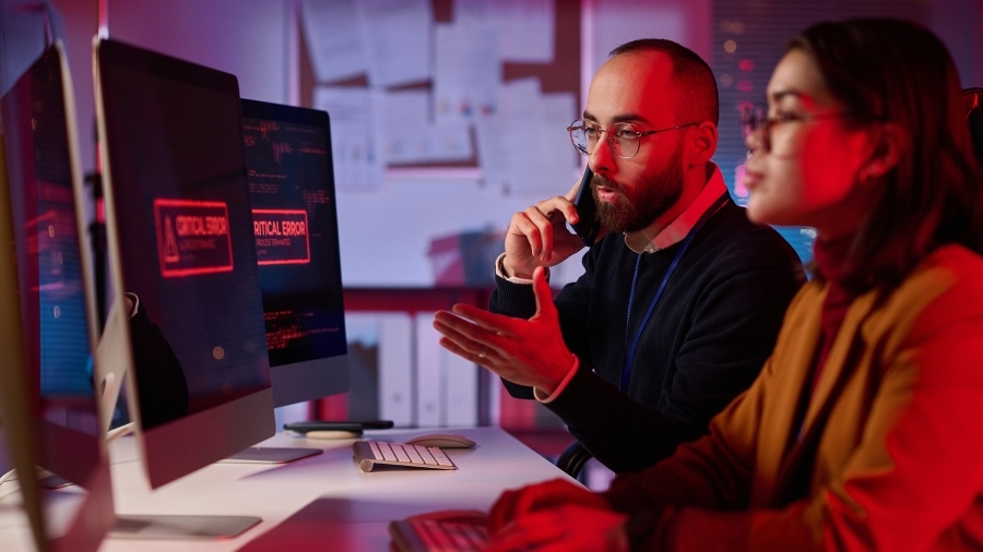Two people looking at a computer screen warning of a security breach.