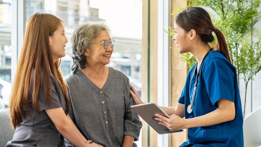 A nurse talking to an older patient and her daughter.